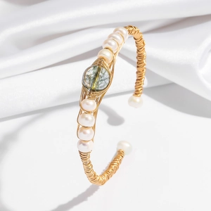Elegant gold wire-wrapped bangle featuring natural pearls and a green gemstone center