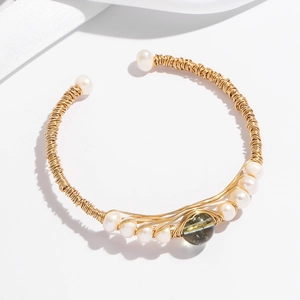 Detail of gold wire wrapped open bangle featuring white pearls and a green bead