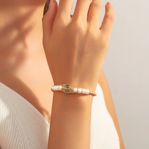 Elegant gold wire-wrapped open cuff bracelet with white pearls and green gemstone