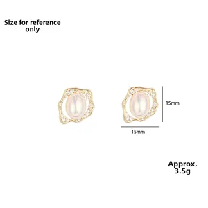 Détail de boucles d'oreilles dorées ondulées avec pierres blanches et zircons