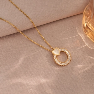Minimalist gold heart necklace with zircon pendant on elegant pink textured fabric