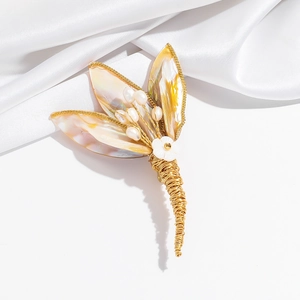 Macro detail of handmade shell flower brooch with pearls and gold wire winding