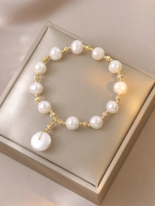 Detail view of natural freshwater pearl bracelet with golden beads on a silk background