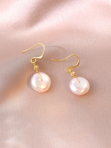 Close-up of pearl drop earrings with gold wire handmade wrap on silk fabric background