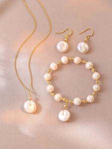 Detailed set of natural freshwater pearl necklace, earrings and bracelet on pink silk