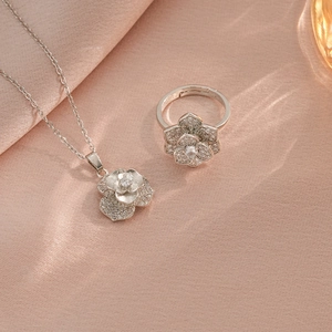 Parure collier et bague fleur argentée avec zircons brillants sur fond en soie