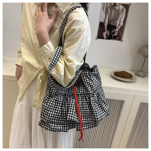Detail view of gingham tote bag with layered ruffles and vibrant orange drawstring accents