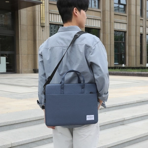 Waterproof navy blue laptop bag with shoulder strap shown in a city street setting