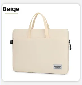 Detail of the beige canvas laptop bag featuring a top handle and woven fashion label