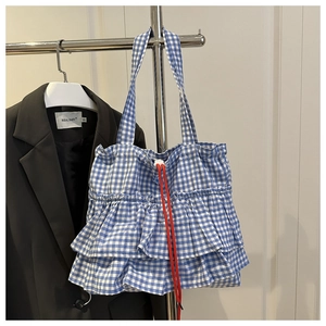 Detail of blue gingham tote bag with red drawstring and triple-layered ruffle design