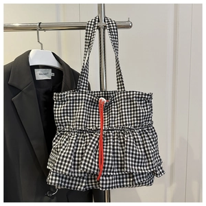 Detail of black and white checkered tote bag with double ruffles and red drawstring accent