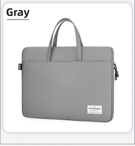 Detail view of a gray canvas laptop bag featuring a fashion label and metal zipper head