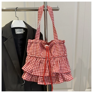 Detail of red checkered tote bag featuring double-layered ruffles and drawstring closure