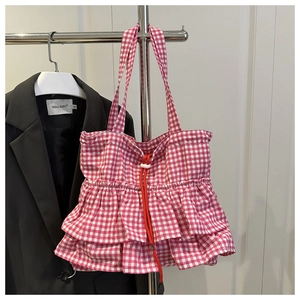 Detail of pink plaid tote bag featuring tiered ruffles and a red drawstring closure