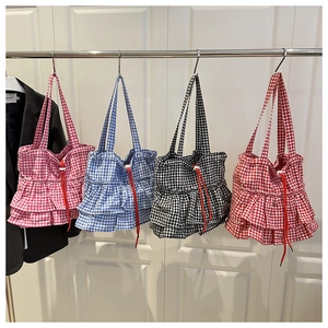 Detail of four plaid tote bags with unique pleated bottom and red drawstring closure