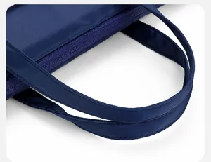 Close-up of the reinforced double handles and neat stitching on a dark blue laptop bag