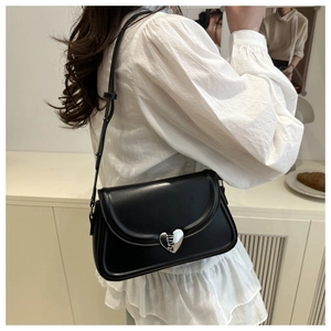 Vue latérale d'un sac à bandoulière en cuir noir avec boucle cœur en métal argenté