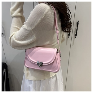 Détail du sac bandoulière en cuir rose avec boucle cœur argentée sur un mannequin