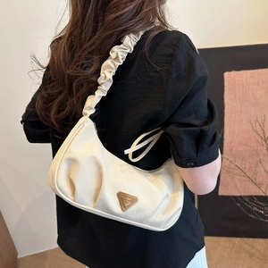 Minimalist beige crescent shoulder bag with ruched strap shown on a model