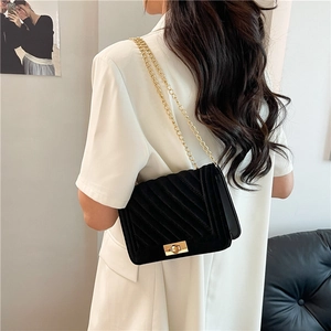 Klassische schwarze Stepptasche mit goldener Kette auf einem weiblichen Modell