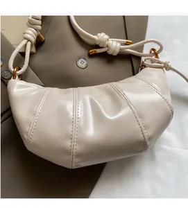 Close-up of beige croissant bag showing pleated stitching and knotted strap details