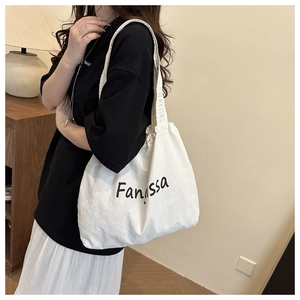 White canvas bucket bag with black logo shown on shoulder in a warm home setting