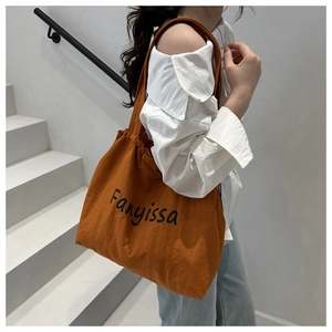 Gros plan d'un sac cabas orange caramel avec imprimé Fanyissa sur un escalier