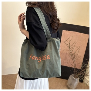 Olive green canvas bucket bag with orange Fanyissa print shown on model in home setting