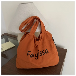 Detail of the large orange fabric shoulder bag with Fanyissa text and drawstring closure