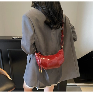 Detail of burgundy crescent bag featuring vertical pleats and high-gloss leather finish