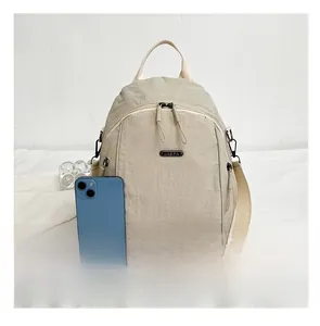 Detail of beige nylon backpack with metal logo and smartphone for size scale