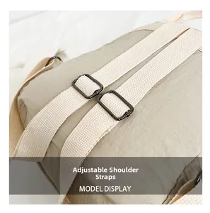 Detail of adjustable nylon shoulder straps with black metal buckles on a beige backpack