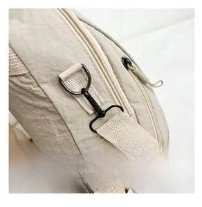 Close-up of gunmetal hardware hooks and zippers on beige nylon commuter backpack