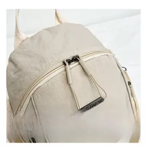Detail of beige nylon backpack showing water-resistant fabric and smooth dual zippers