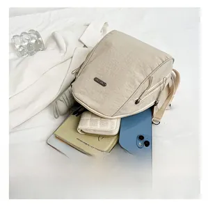 Detail view of the spacious inner compartment of the beige nylon backpack with daily items