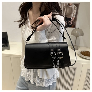 Close-up of black crossbody bag with silver buckle belts and delicate chain detail