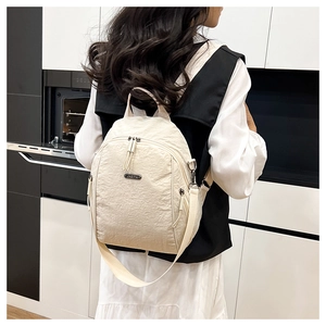 Detail of a beige nylon backpack with pleated texture and adjustable straps shown on model