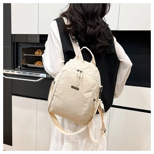 Detailed macro view of cream nylon backpack fabric with premium JING PIN metal logo plaque