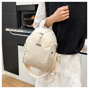 Detail of cream nylon backpack featuring crinkled texture fabric and JING PIN metal plate