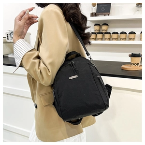 Side view of lightweight black nylon backpack worn over a beige suit in a cafe
