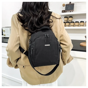 Mini black nylon backpack shown on shoulder with stylish khaki blazer outfit