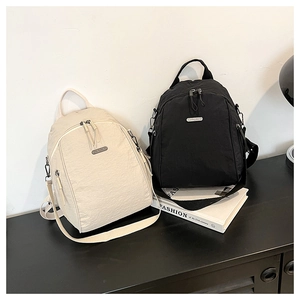 Close-up of lightweight nylon backpacks in beige and black with metallic logo details