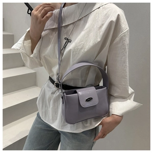 Détail d'un sac seau en cuir lilas avec plaque métallique et poignée supérieure