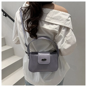Détail d'un sac à bandoulière en cuir lavande avec logo JWHN posé sur un escalier