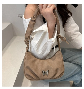 Détail d'un sac hobo marron tissé avec fermoir papillon argenté et bandoulière plissée