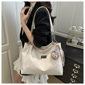 Detail of white glossy tote bag featuring silver chain straps and decorative plush bunny