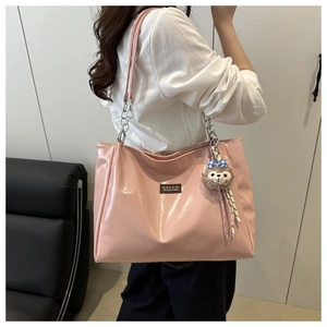 Pink glossy tote bag with silver chain strap and plush bear charm on side detail