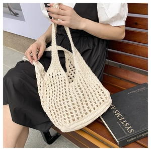 Detailed close-up of a white knitted tote bag with hollow mesh pattern on wooden bench
