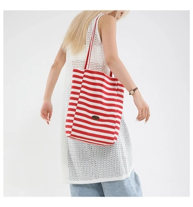 Detail view of red and white striped large canvas tote bag on female model's shoulder