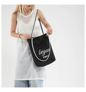 Detail of black canvas tote bag with merci print and soft white cotton rope handles